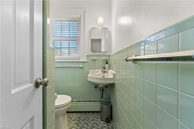 bathroom with a baseboard radiator, tile patterned flooring, sink, tile walls, and toilet