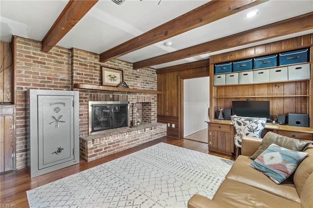 living room featuring dark wood-type flooring, wooden walls, beam ceiling, and a fireplace