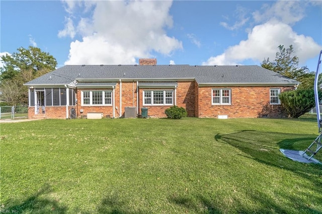 back of property with a sunroom, a lawn, and central air condition unit