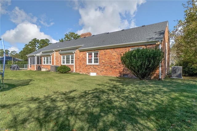 rear view of property featuring central AC unit and a yard