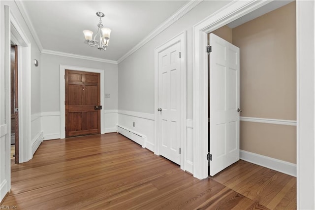 foyer entrance featuring an inviting chandelier, crown molding, hardwood / wood-style flooring, and a baseboard radiator