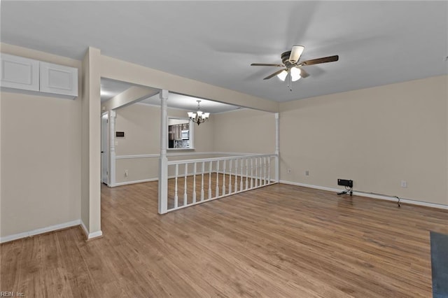 spare room with ceiling fan with notable chandelier and light hardwood / wood-style floors