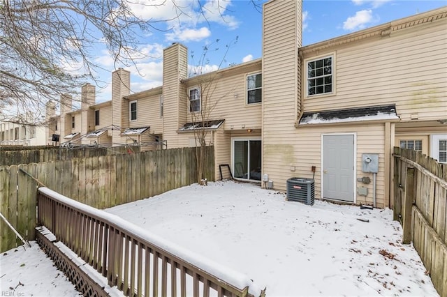 snow covered rear of property featuring central AC