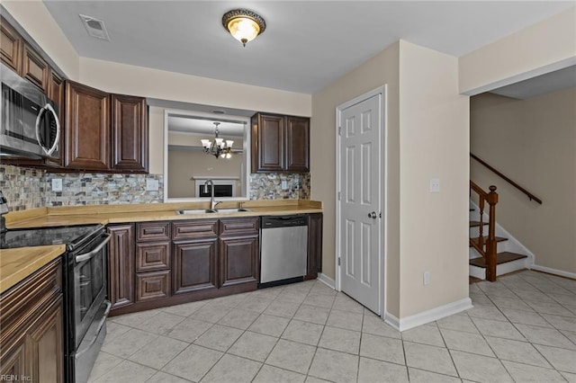 kitchen with sink, light tile patterned floors, appliances with stainless steel finishes, hanging light fixtures, and decorative backsplash