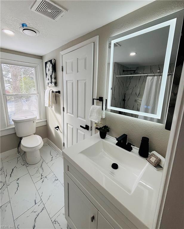 bathroom with vanity, toilet, a textured ceiling, and a shower with shower curtain