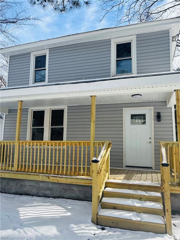 snow covered property entrance with a porch