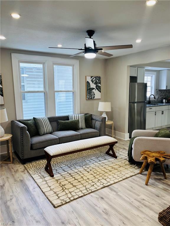 living room featuring sink, light wood-type flooring, and ceiling fan