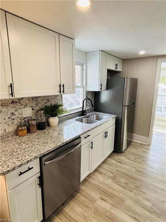 kitchen with sink, light stone counters, white cabinets, and appliances with stainless steel finishes