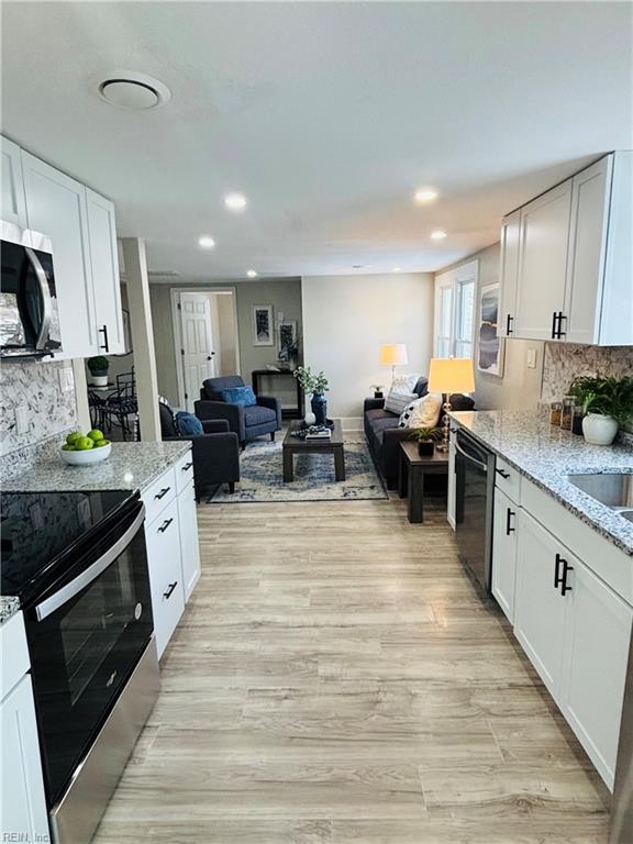 kitchen featuring light stone counters, tasteful backsplash, white cabinetry, and appliances with stainless steel finishes