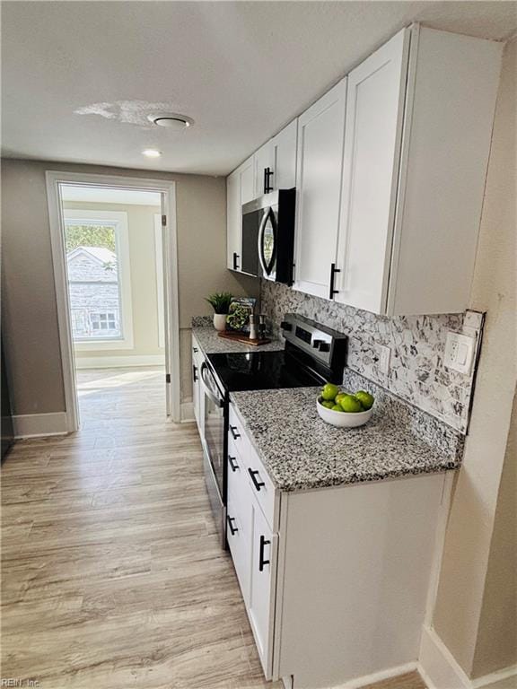 kitchen featuring light stone countertops, white cabinetry, backsplash, and stainless steel appliances