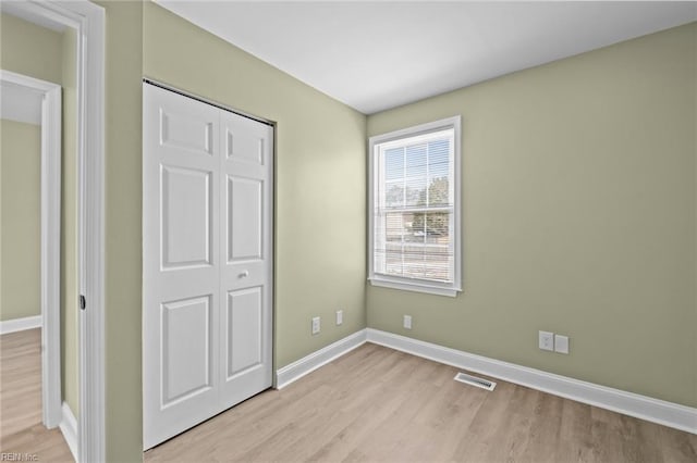 unfurnished bedroom featuring light hardwood / wood-style floors and a closet