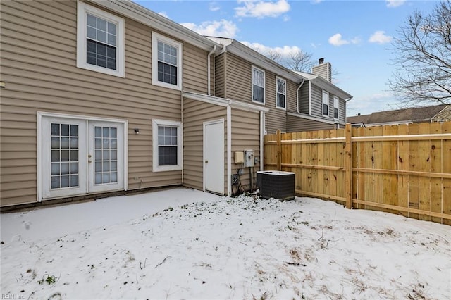 snow covered rear of property featuring cooling unit and french doors