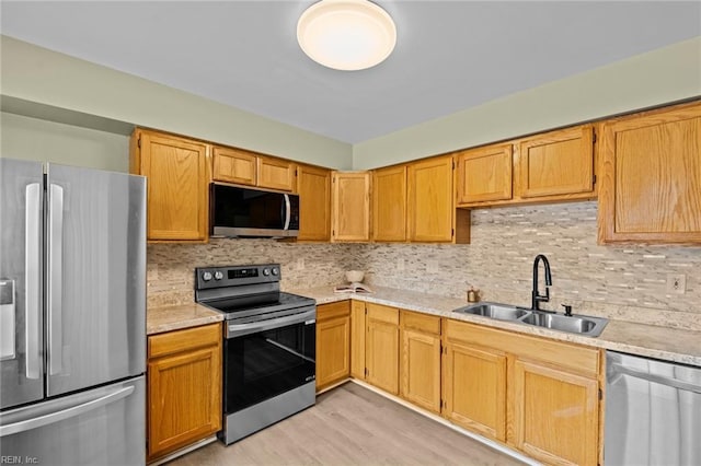 kitchen featuring stainless steel appliances, sink, decorative backsplash, and light hardwood / wood-style flooring