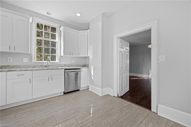 kitchen featuring dishwasher, pendant lighting, sink, light stone countertops, and white cabinets