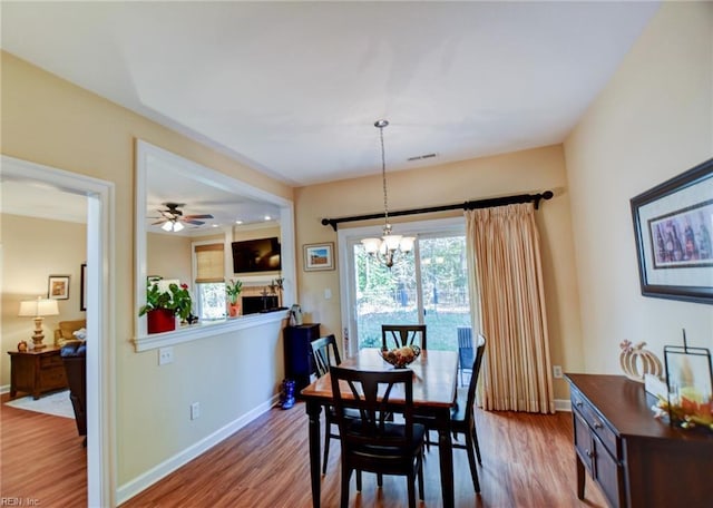 dining room featuring ceiling fan with notable chandelier and hardwood / wood-style floors