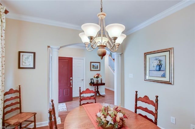 dining area with ornate columns, light hardwood / wood-style flooring, ornamental molding, and a notable chandelier