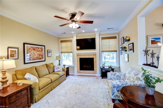 living room with ceiling fan, crown molding, plenty of natural light, and a tile fireplace