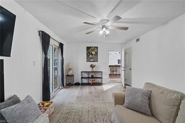 living room featuring ceiling fan, plenty of natural light, and light hardwood / wood-style flooring