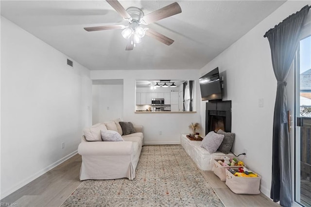 living room featuring ceiling fan and light hardwood / wood-style flooring