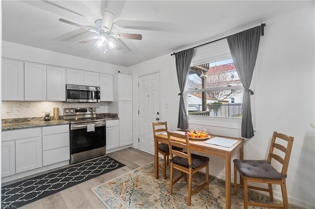 kitchen with ceiling fan, white cabinetry, stainless steel appliances, and light wood-type flooring