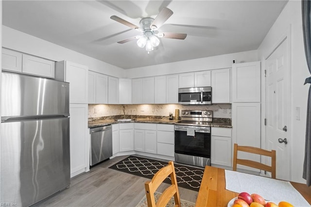 kitchen with stainless steel appliances, white cabinetry, light hardwood / wood-style floors, and backsplash