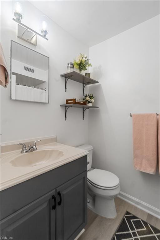 bathroom featuring hardwood / wood-style flooring, toilet, and vanity