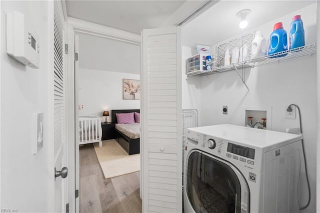 clothes washing area with light hardwood / wood-style floors and washer / dryer