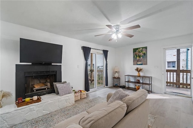 living room with a fireplace, light hardwood / wood-style flooring, a wealth of natural light, and ceiling fan