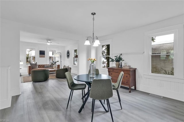 dining space with ceiling fan with notable chandelier and wood-type flooring