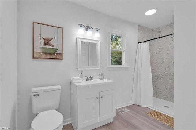 bathroom with a shower with curtain, wood-type flooring, toilet, and vanity