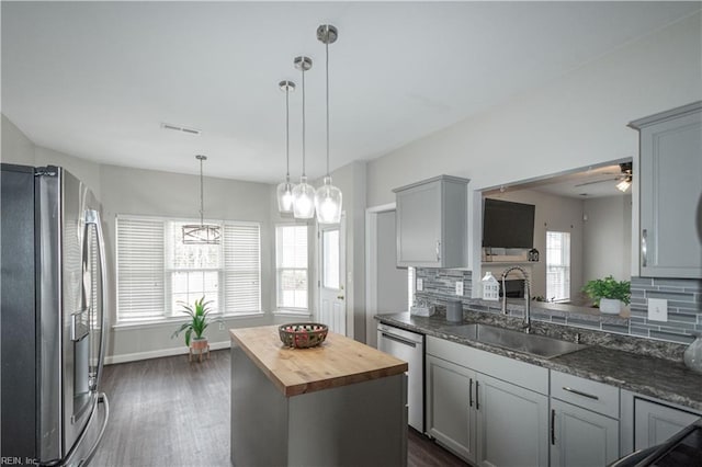 kitchen featuring appliances with stainless steel finishes, sink, tasteful backsplash, a center island, and wood counters