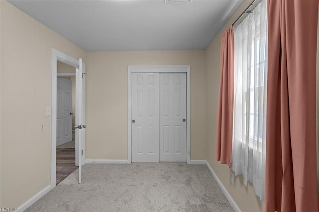 unfurnished bedroom with multiple windows, light colored carpet, and a closet