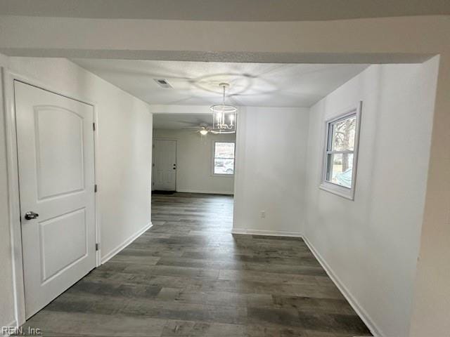 unfurnished dining area featuring a healthy amount of sunlight, an inviting chandelier, and dark hardwood / wood-style flooring