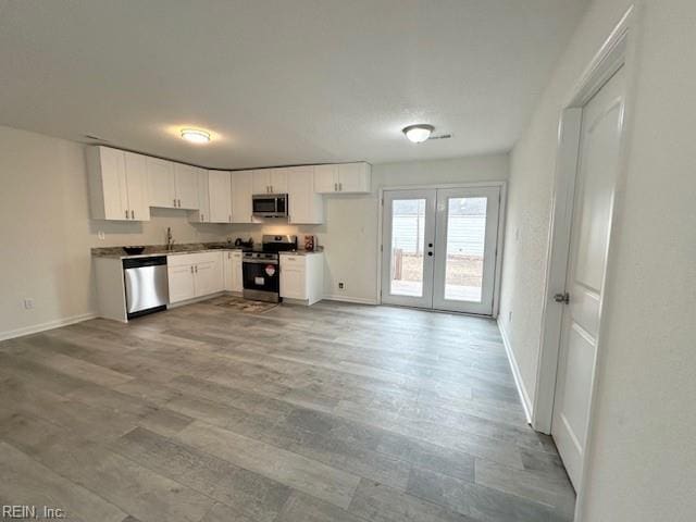 kitchen with light hardwood / wood-style flooring, french doors, sink, appliances with stainless steel finishes, and white cabinets