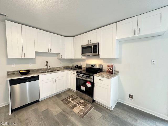 kitchen with sink, white cabinetry, appliances with stainless steel finishes, and dark wood-type flooring