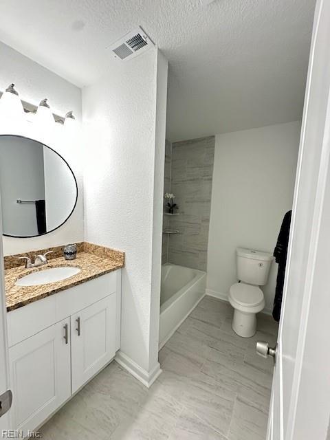 full bathroom with vanity, toilet, tiled shower / bath, and a textured ceiling