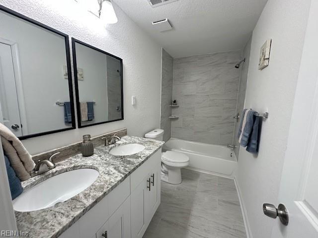 full bathroom featuring vanity, toilet, tiled shower / bath, and a textured ceiling