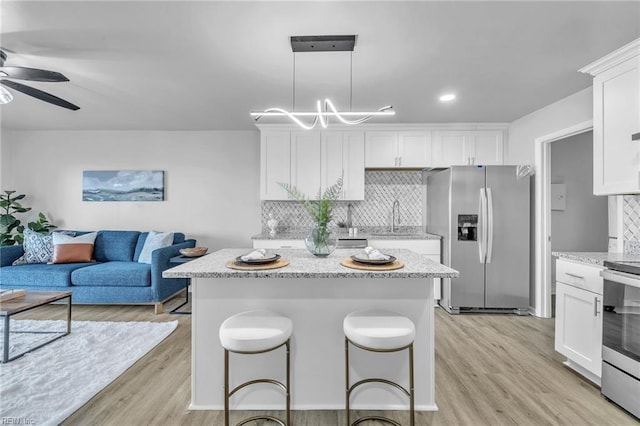 kitchen featuring hanging light fixtures, tasteful backsplash, appliances with stainless steel finishes, and white cabinets