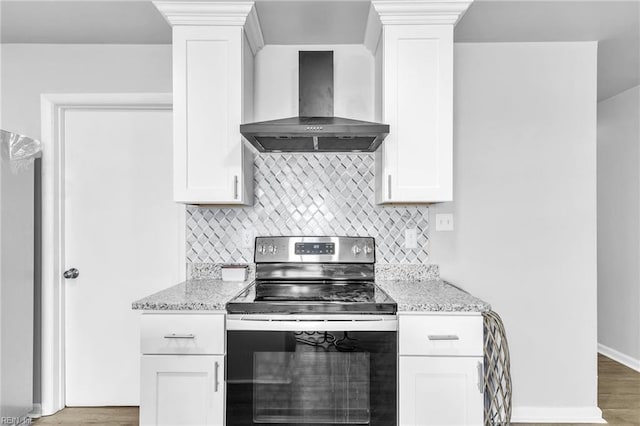 kitchen with white cabinetry, stainless steel electric range, light stone countertops, and wall chimney exhaust hood