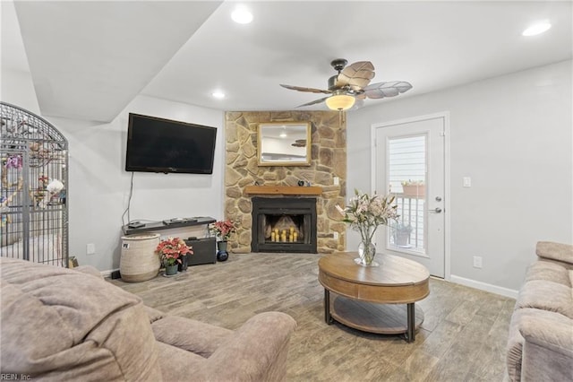 living room with ceiling fan and a stone fireplace