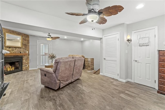 living room featuring wood-type flooring, a fireplace, and ceiling fan