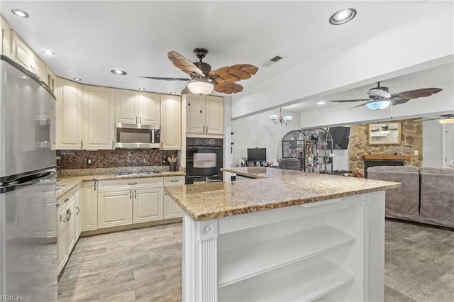 kitchen with ceiling fan, appliances with stainless steel finishes, tasteful backsplash, light stone counters, and a fireplace