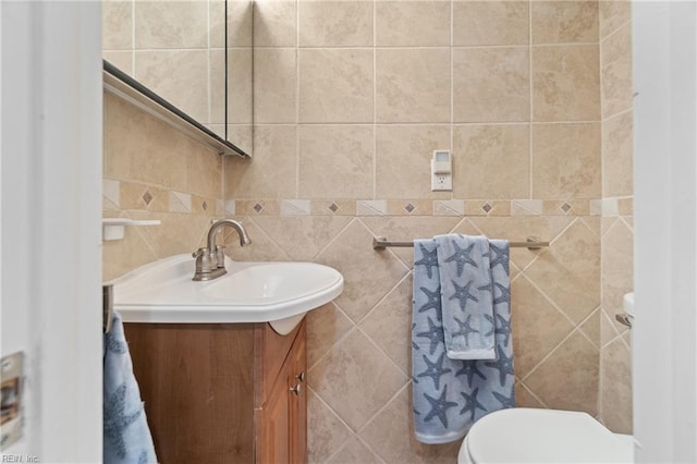 bathroom featuring vanity, toilet, and tile walls