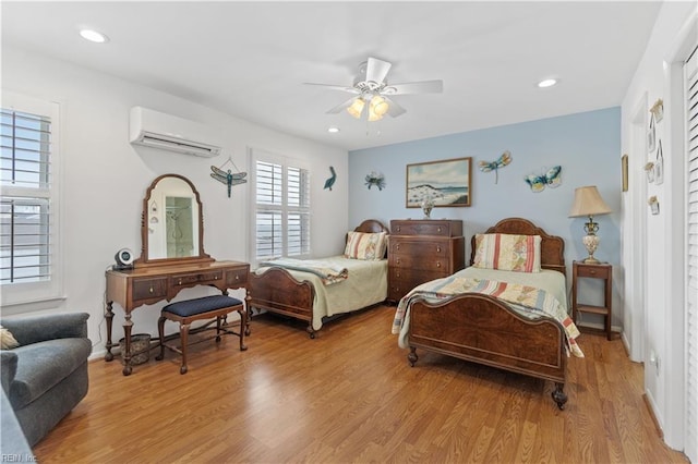 bedroom with ceiling fan, a wall mounted AC, and light wood-type flooring