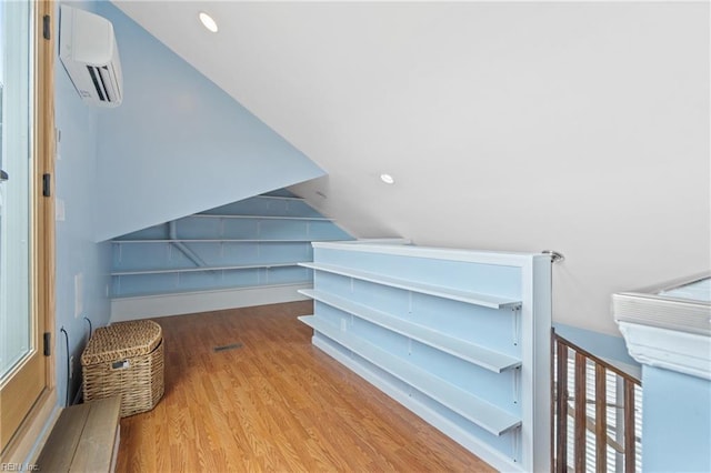 bonus room featuring light hardwood / wood-style flooring, a wall mounted AC, and vaulted ceiling