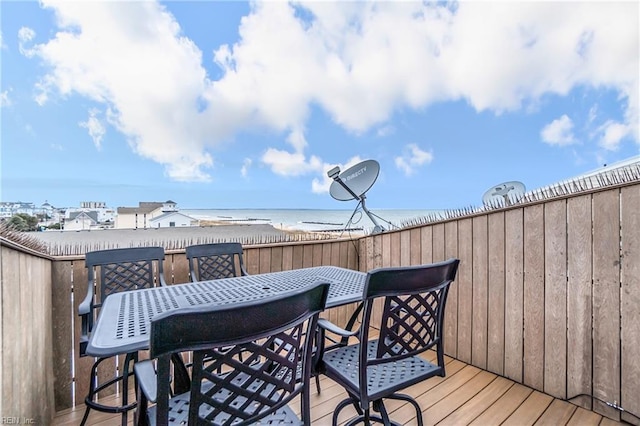 wooden terrace featuring a water view and a view of the beach