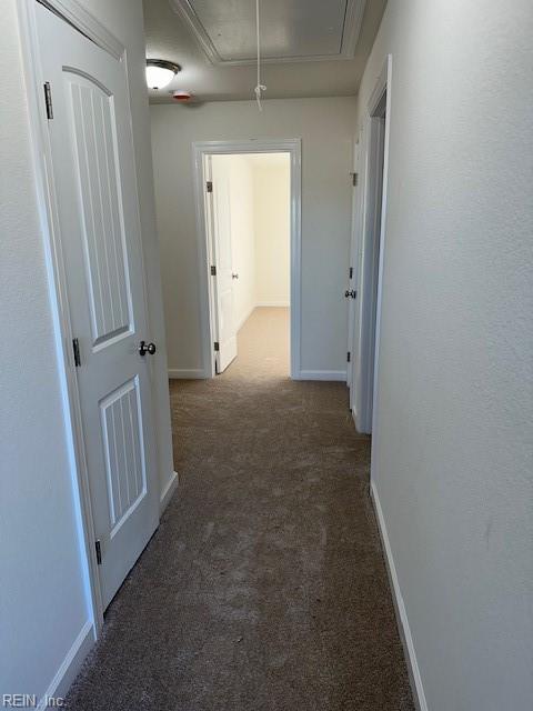 hall featuring dark colored carpet