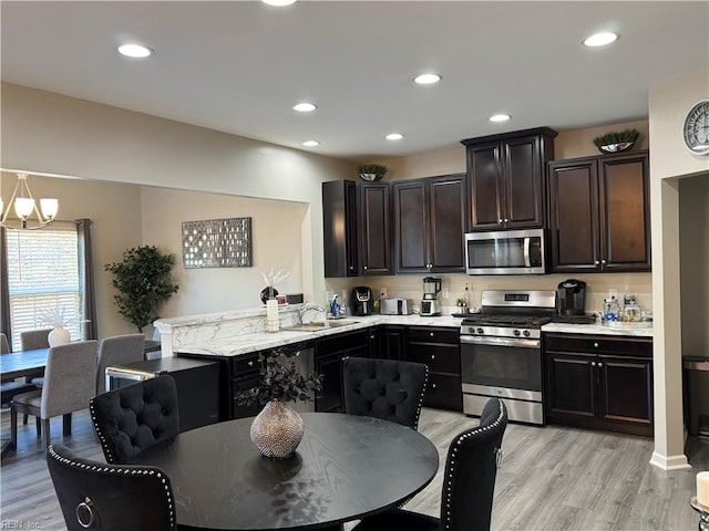 kitchen featuring light hardwood / wood-style floors, sink, dark brown cabinetry, decorative light fixtures, and stainless steel appliances