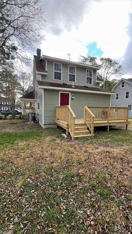 rear view of property featuring a deck and a lawn