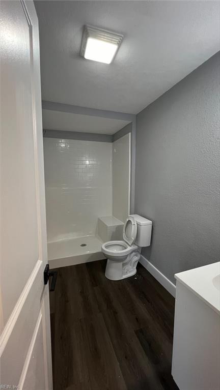 bathroom featuring hardwood / wood-style floors, toilet, walk in shower, and vanity